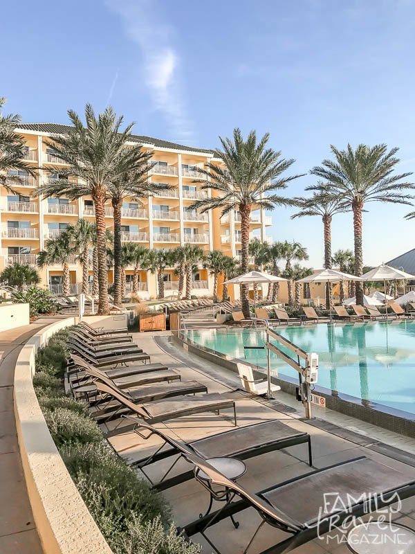 Omni Amelia Island Plantation pool area with chairs and palm trees in front of resort building