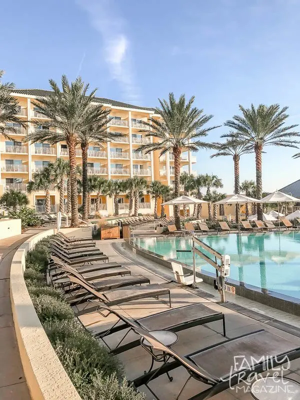 Omni Amelia Island Plantation pool area with chairs and palm trees in front of resort building