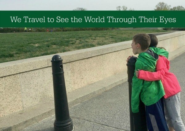 Kids looking at monument. Banner says "We travel to see the world through their eyes"