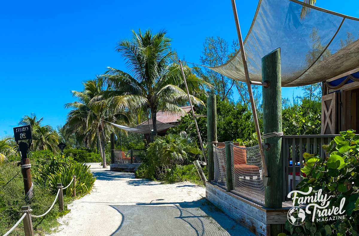 A path leading to cabanas with trees and greenery.