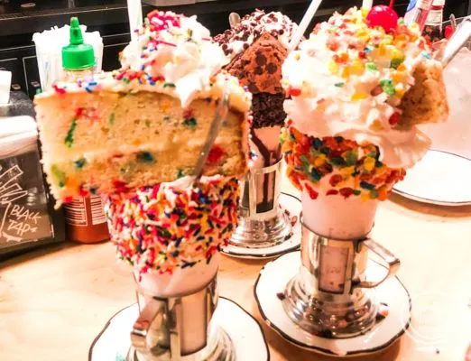 Colorful milkshakes with cake and cereal on top