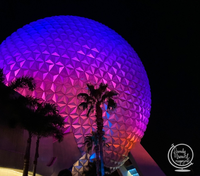 Epcot at night with Spaceship Earth lit up in purple and pink