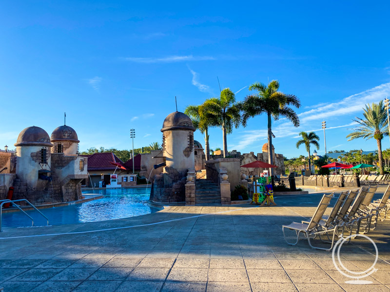 The pirate pool at the Caribbean Beach Resort with lawn hairs, towers, stairs, and palm trees