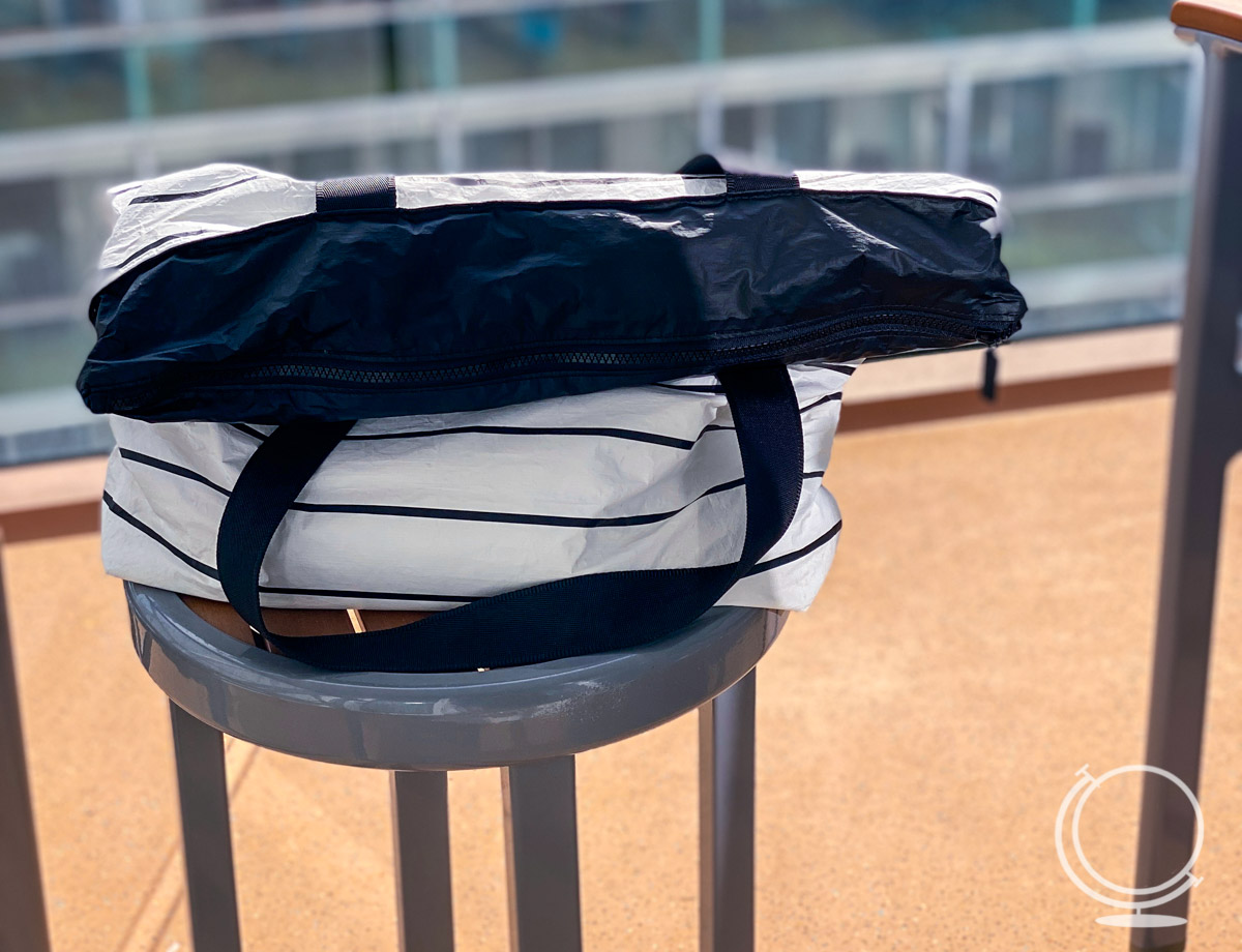 Beach bag sitting on table on cruise stateroom balcony  - what to pack in a cruise carry on bag 