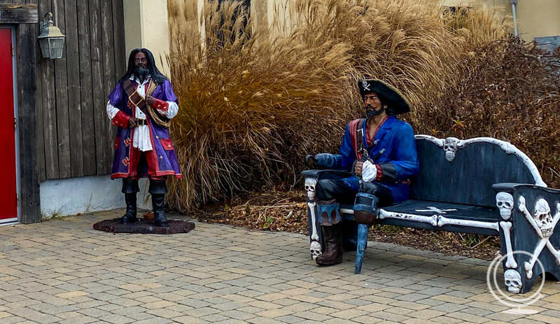 Two pirate statues outside the pirate museum, including one sitting on a bench 