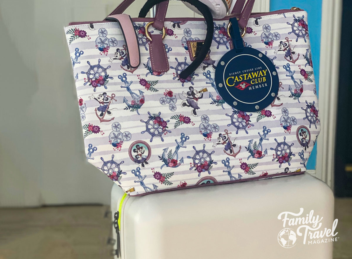 Disney tote bag with round luggage tag on top of suitcase