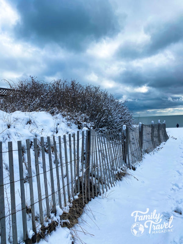 Snow on a beach with wooden fence and snow-covered dune