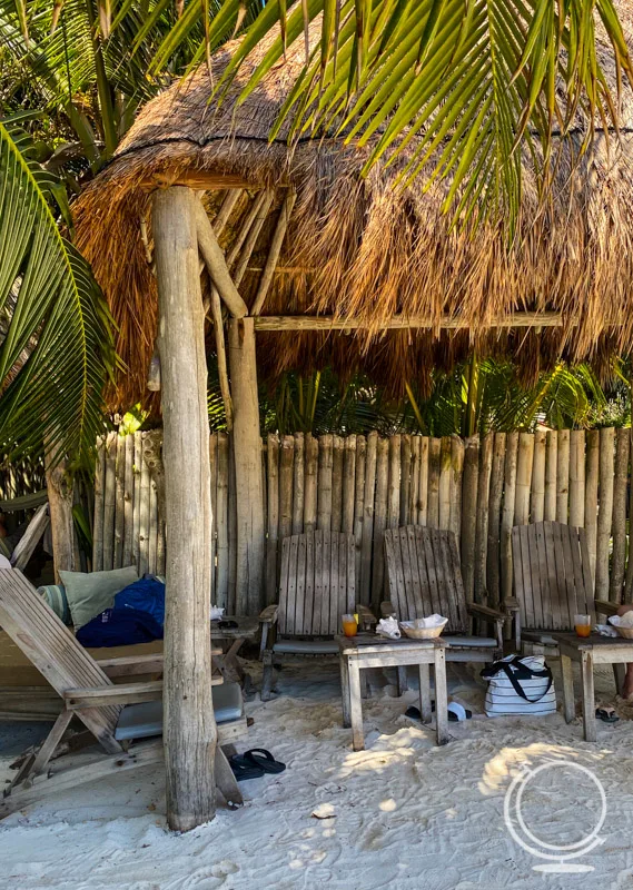 Our pergola with wooden chairs, tables, and a beach bed, with drinks and chips on the tables. 