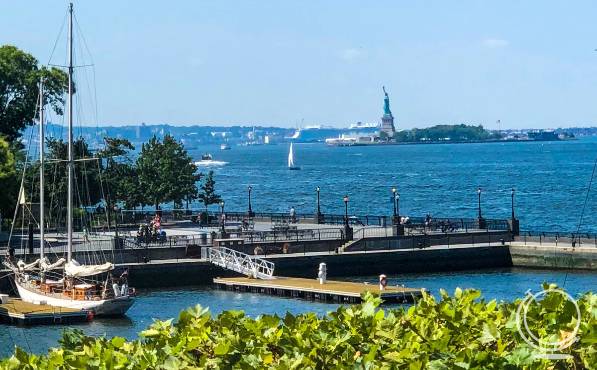 Manhattan waterfront with pier and boat in the foreground, and Statue of Liberty in the background. - 4 Days in NYC