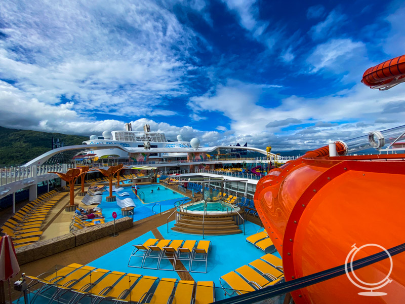 Pool deck on the Wonder of the Seas with pool loungers and orange water slide