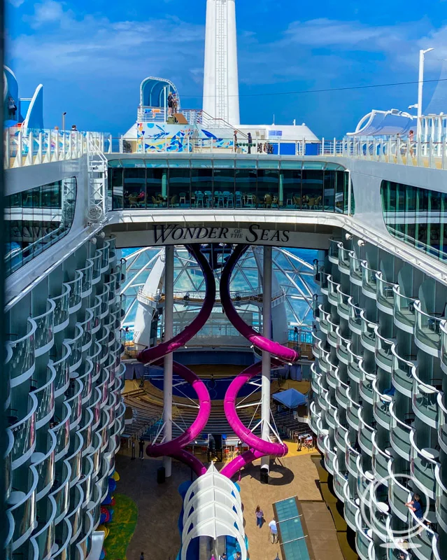 One of the atriums on the Wonder of the Seas with stateroom balconies and two purple curving slides
