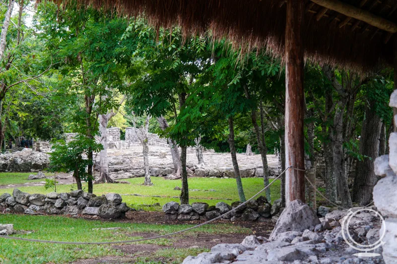 Wall ruins in the background with trees and a roped off area in the foreground. 