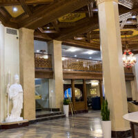 Lobby of the Marriott Syracuse with a statue, columns, ornate decorative ceilings, and gold-toned gates.