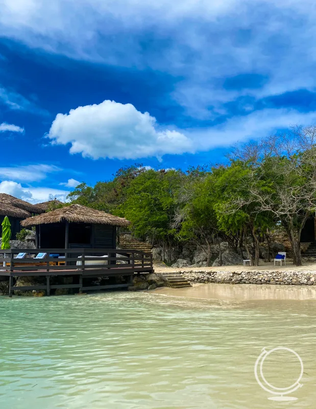 An overwater bungalow with lush vegetation in the background.