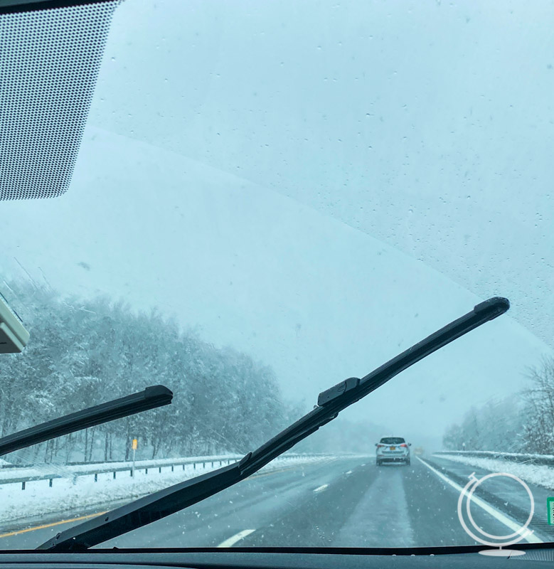 Snow falling on car windshield during a road trip