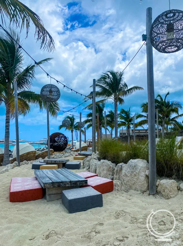 low tables with cushions, palm trees, overhead lighting on the beach