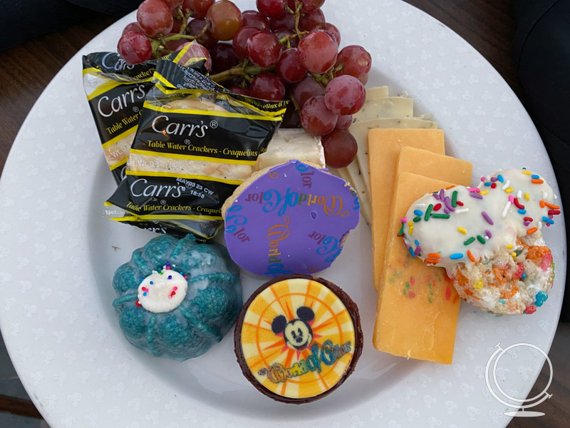 World of Color Dessert Party plate featuring cheese, decorative desserts, grapes, and crackers. 