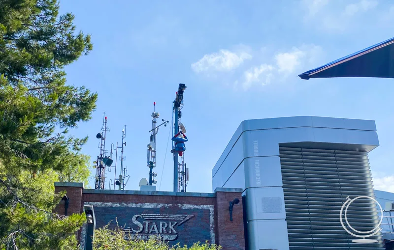 Spider man robot hanging upside down above Stark building at Avengers Campus