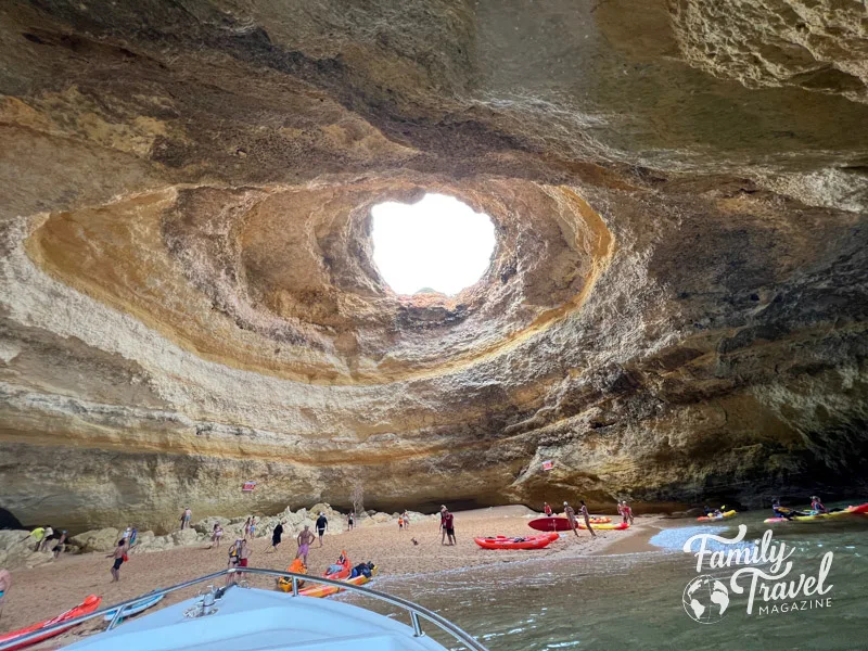 Cave with a hole in the top, and kayakers along the water and beach