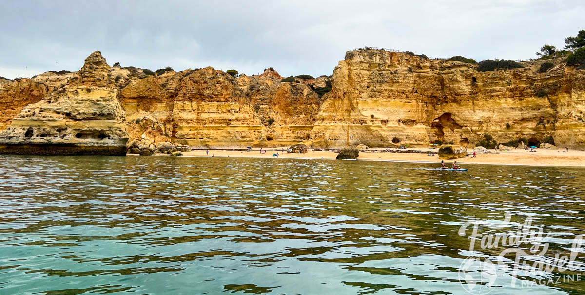 Golden cliffs along coastline with water in foreground