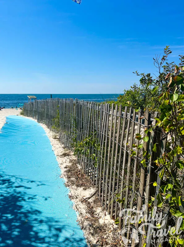 Blue beach carpet leading to sand and water