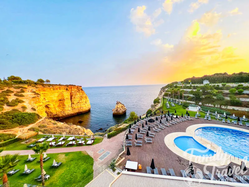 View from Tivoli Carvoeiro Hotel, including cave, cliff, outdoor pool, and beach chairs. 