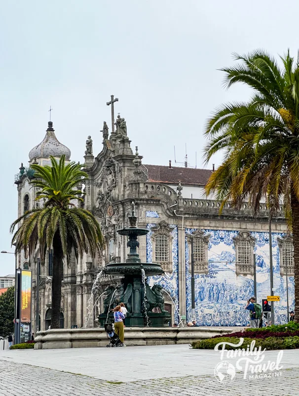 Church with blue and white tiles on the side with fountain and trees in the foreground. 