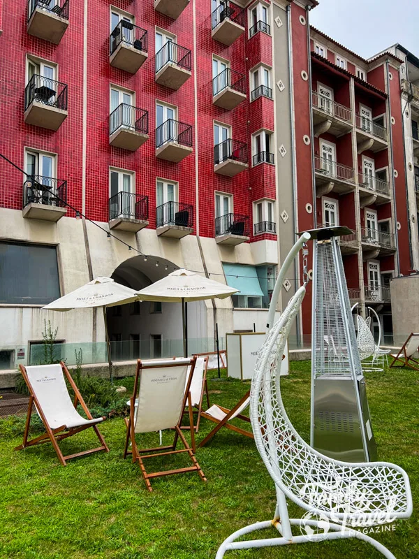 red building with individual balconies around a courtyard with white patio furniture