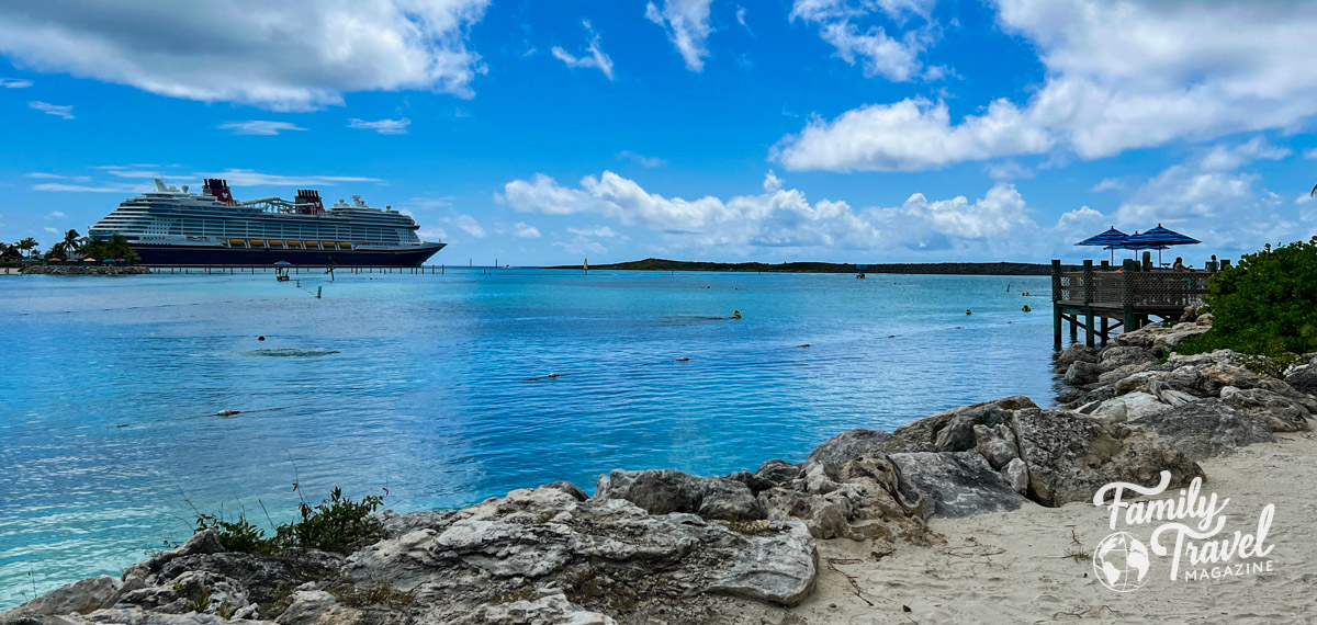 The Disney Wish docked at Castaway Cay with the beach in the foreground and a blue sky