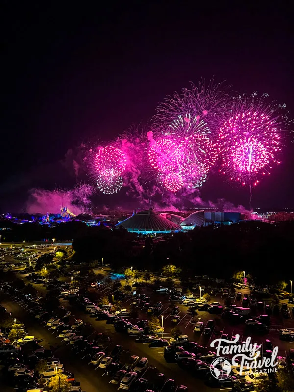 Pink fireworks in dark sky over the Magic Kingdom. 