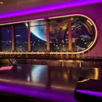 The bar at Star Wars Hyperspace Lounge with bottles along the counter and screen/window into space.