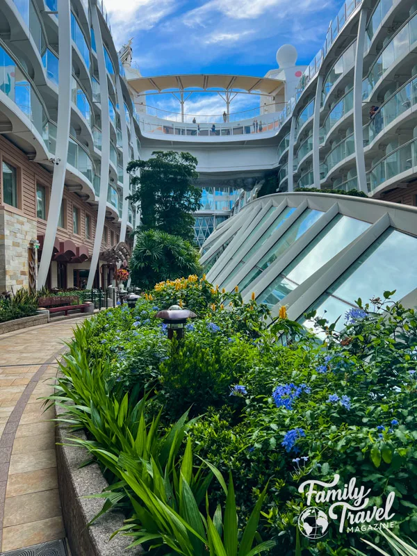 Central Park on the Allure of the Seas with glass structure and plants along a path surrounded by staterooms