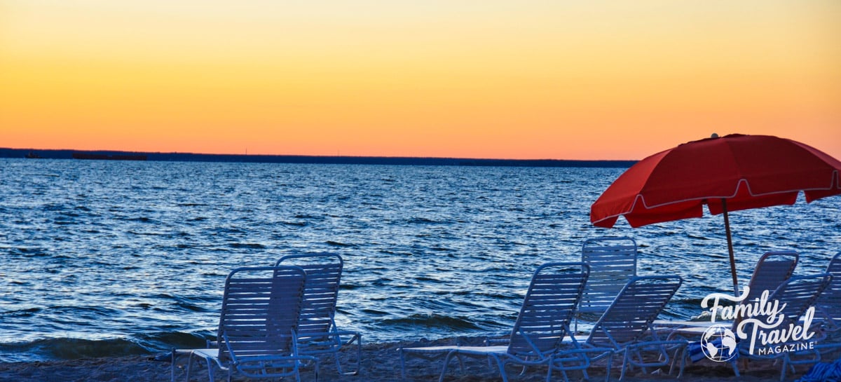 lounge chairs and orange umbrella along the beach at sunset