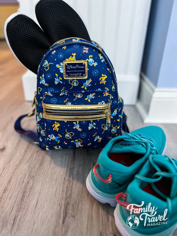sneakers in front of mini Disney backpack with black shoes popping out of it