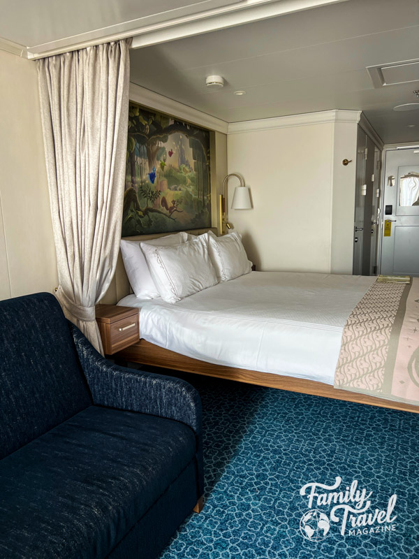 Stateroom with couch and bed with a mural above 