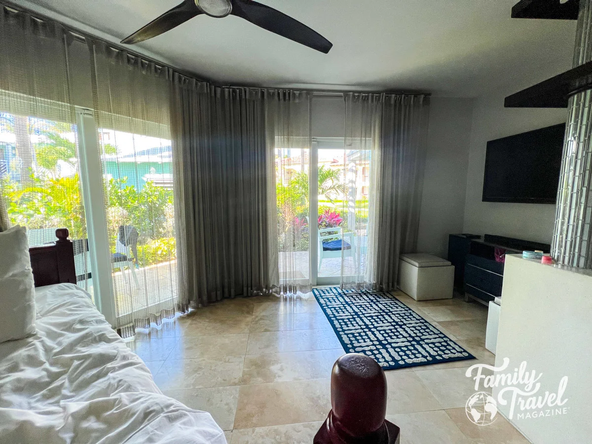 Living room in Seaside villa with couch/bed, rug, tv stand, and entrance to patio area.