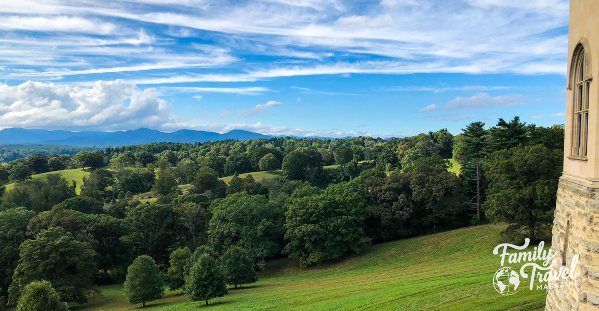 Green rolling hills and a blue sky with clouds and a small peek of a building at the Biltmore resort, one of the best things to do in Asheville with kids . 