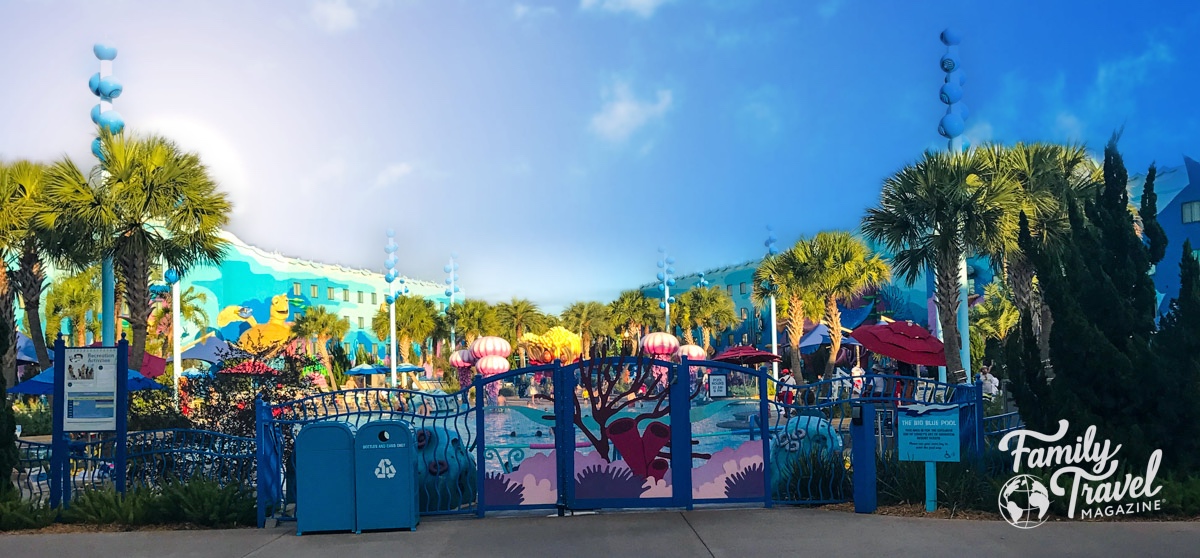 The Deep Blue Pool from the other side of the fence with colorful Nemo decor and palm trees at Disney's Art of Animation - the best Disney World hotel for toddlers