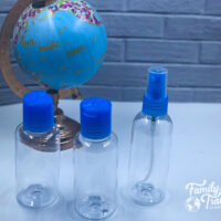 clear toiletry bottles with blue caps in front of a blue and pink globe