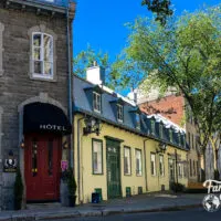 A street with buildings, trees, and a small hotel in Quebec City, one of the best summer family vacation destinations.