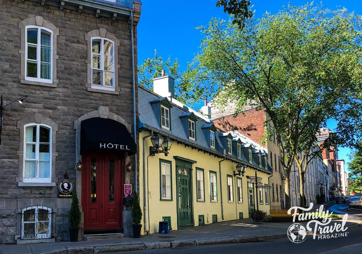 A street with buildings, trees, and a small hotel in Quebec City, one of the best summer family vacation destinations. 