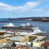 Two cruise ships docked along Quebec City waterfront with buildings in the foreground