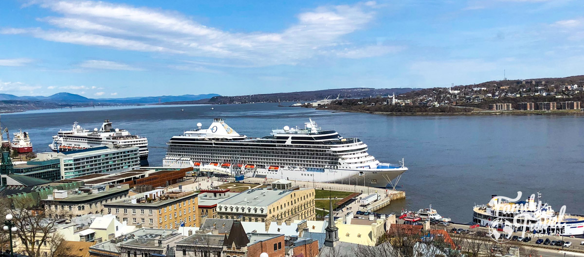 Two cruise ships docked along Quebec City waterfront with buildings in the foreground 