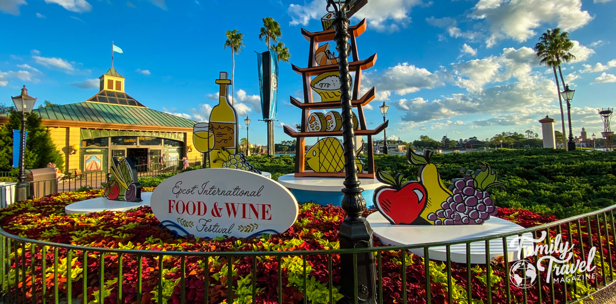Display advertising the Food and Wine Festival with cut outs of fruit wine, and sushi among plants. 
