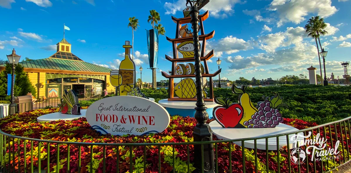 Display advertising the Food and Wine Festival with cut outs of fruit wine, and sushi among plants.