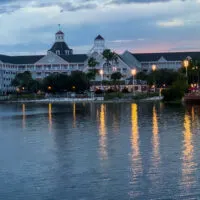 The Disney World Yacht Club from afar at sunset with lighthouse and buildings in front of the water