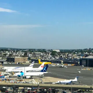Outside of Boston Logan airport with planes, hotel, and Boston Logan Jetblue hanger and highway in the foreground.