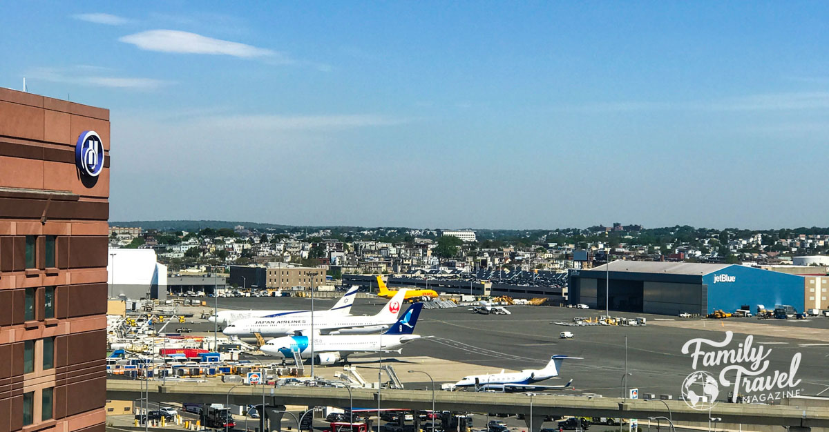 Outside of Boston Logan airport with planes, hotel, and Boston Logan Jetblue hanger and highway in the foreground. 