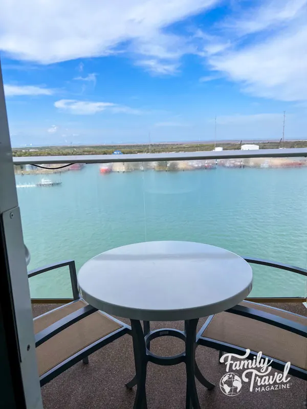 Stateroom balcony with table and two chairs with turquoise waters 