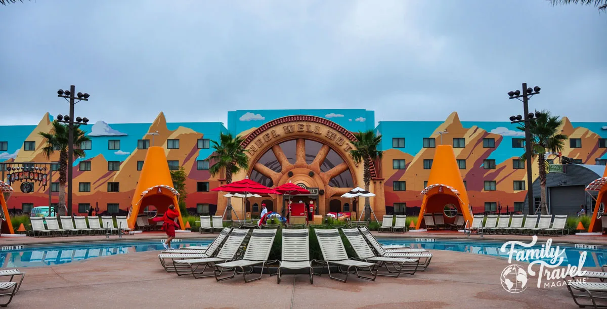 Wheel Well Hotel facade in front of hotel with cone cabanas, lounge chairs, and pool in the foreground